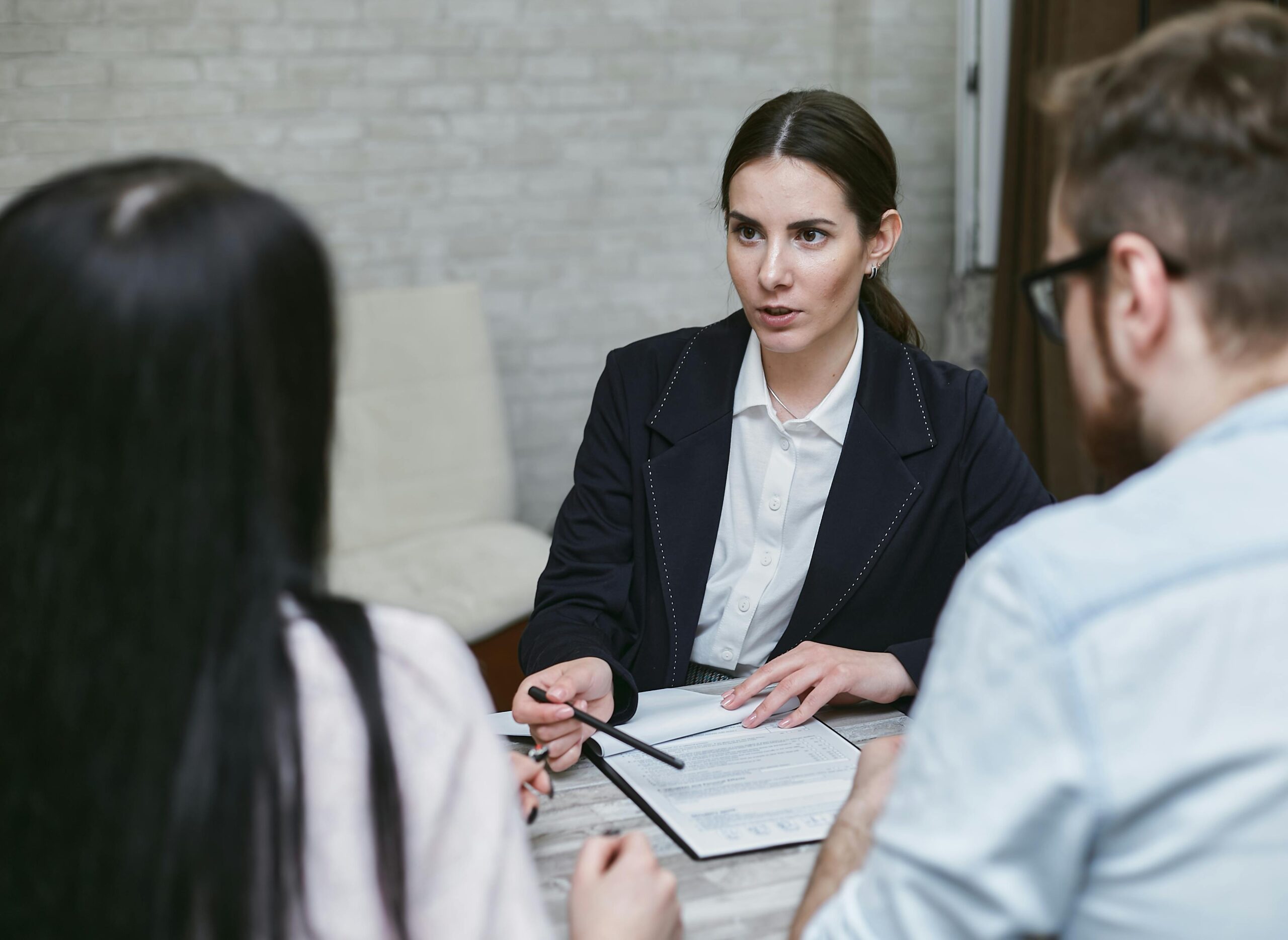 Three colleagues engaged in a business meeting discussing documents at a table indoors.